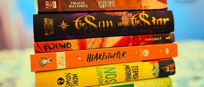 ‘An expanded Pride flag stack of 11 queer books | Predestined, Red, White, and Royal Blue, Self-Made Boys, Legends and Lattes, The Sun and The Star, Bound The Contract, Heartstopper, Kings Rising, Wayward Son, Magnus Chase and the Gods of Asgard & Spell Bound’ — “11 Books You Should Add to Your Rainbow Stack this Pride”, Kat Vancil, The Saga
